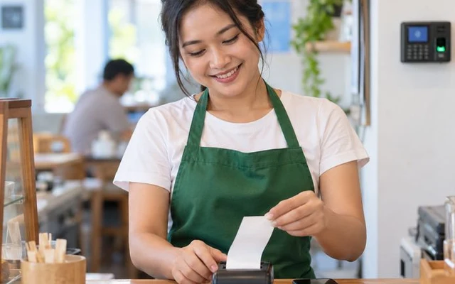 Kasir merobek struk dari printer thermal Bluetooth di meja kasir