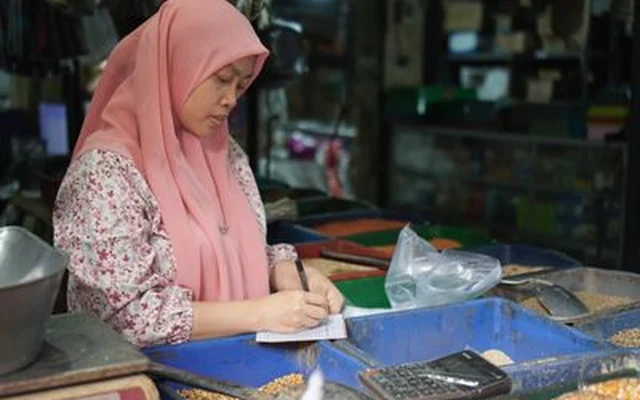 Pedagang warung mencatat pembukuan kasbon pelanggan