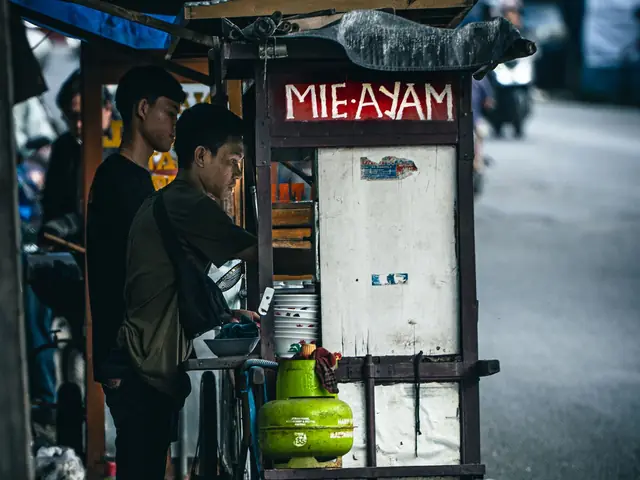 Pedagang mi ayam menyiapkan pesanan di gerobaknya