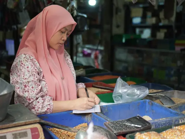 Pedagang sembako mencatat penjualan di lapak